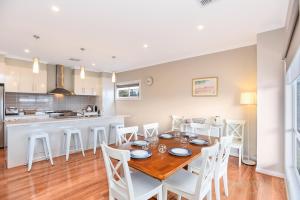 cocina y comedor con mesa de madera y sillas en Seahaven - Sellicks Beach - C21 SouthCoast Holidays en Sellicks Beach