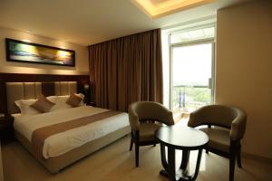 a hotel room with a bed and a table and a window at The Zabeer Jashore in Jessore