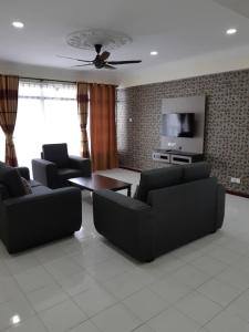 ein Wohnzimmer mit 2 Sofas und einem TV in der Unterkunft Pantai Puteri Homestay in Kampong Lereh