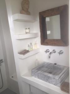 a white bathroom with a sink and a mirror at The Hill Top House in Kea in Ioulis