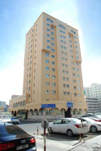 Basma Residence Hotel Apartments في الشارقة: مبنى كبير به سيارات تقف في موقف للسيارات