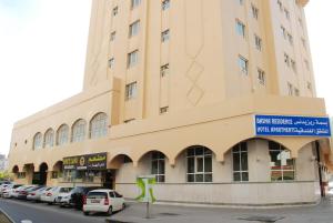 un gran edificio con coches estacionados frente a él en Basma Residence Hotel Apartments, en Sharjah