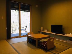 a living room with a table and chairs and a television at B&B Izumi Nikko in Nikko