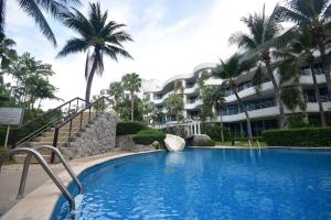 a swimming pool in front of a building with palm trees at Hua Hin Beachfront Condo in Hua Hin