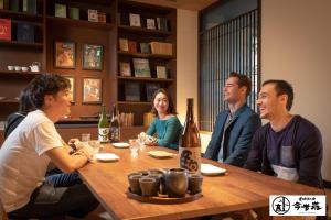 a group of people sitting around a table in a restaurant at Konjaku-So Dotonbori Garden SPA Stay in Osaka
