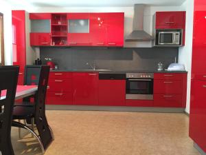 a red kitchen with red cabinets and a table at Ferienwohnung Familie Meinschad in Rietz