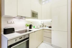 a white kitchen with white cabinets and a sink at DownTown Design Flat in Budapest