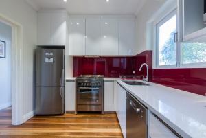 a kitchen with white cabinets and a stainless steel refrigerator at Cottesloe Beach Deluxe Apartment in Perth