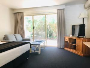 Habitación de hotel con cama, sofá y TV en Nagambie Motor Inn and Conference Centre, en Nagambie