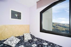 シエラネバダにあるApartamento con cochera edificio Monte Oizのベッド1台と大きな窓が備わる客室です。