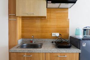スラバヤにあるStrategic Studio Apartment at Orchard Mansion Supermall By Travelioのシンクと冷蔵庫付きのキッチン