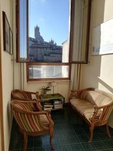 Duas cadeiras e um sofá num quarto com uma janela em Albergo Bernini em Siena