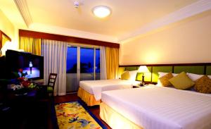 a hotel room with two beds and a television at Kalim Resort - SHA Plus in Patong Beach
