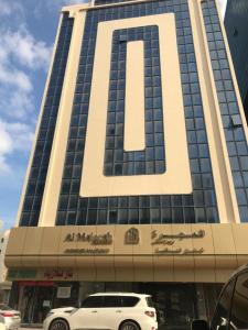Al Majarah Residence في الشارقة: سيارة دفع رباعي بيضاء متوقفة أمام مبنى طويل