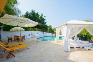 a patio with a pool and an umbrella and chairs at Bozis Private Pool Villa, Siviri in Siviri