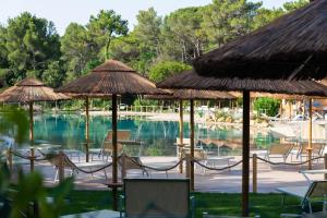 een groep stoelen en parasols naast een zwembad bij Camping Village Le Esperidi in Marina di Bibbona