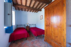 um quarto com duas camas vermelhas e uma televisão em Casa Verniano em Pieve a Scuola