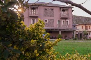 a pink house with a green field in front of it at Akrolimnion Hotel in Ioannina