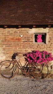 un vélo garé devant un mur de briques orné de fleurs dans l'établissement Chezlesgoyp, à Cosges