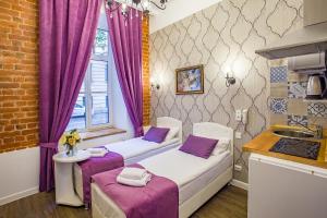twee bedden in een kleine kamer met paarse gordijnen bij Petrovskiy Art Loft in Sint-Petersburg