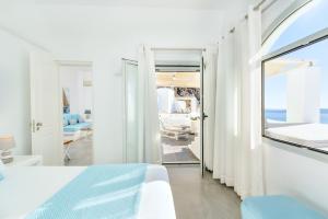 a white bedroom with a view of the ocean at Agali Houses in Firostefani