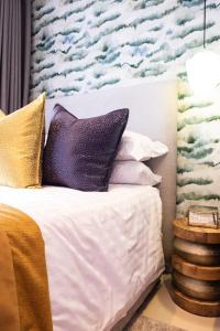 1 dormitorio con 1 cama con almohadas moradas y doradas en The Wilcrest Apartment, en Randjesfontein