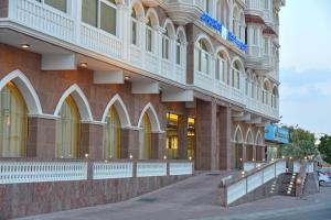 a large building on a street next to a sidewalk at Muscat Plaza Hotel in Muscat