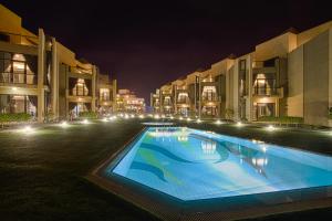 a large swimming pool in a courtyard at night at Faris Villas للعائلات فقط-الصفحة الرسمية لمنتجع فلل فارس in Al Khīrān