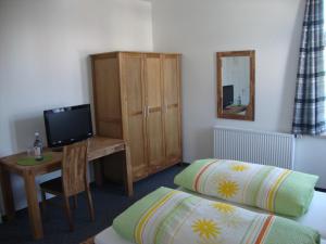 a room with two beds and a desk with a television at Raffelberger Hof in Mülheim an der Ruhr