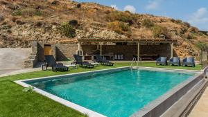 a swimming pool in a yard with chairs and a house at Anastasis Luxury Villa Andros With Heated Pool in Sinétion