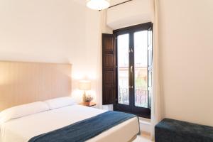a bedroom with a bed and a window at Suites Campo del Príncipe in Granada