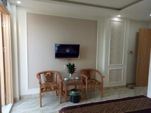 sala de estar con 2 sillas, mesa y TV en Royal Hotel en Hai Phong