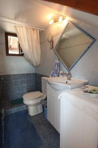 a bathroom with a sink and a toilet and a mirror at Traditional studio in Skiros