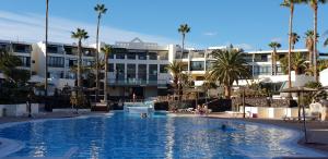 una gran piscina con palmeras y edificios en CASA SERAFIN primera linea 40B, en Costa Teguise