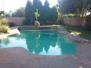 a swimming pool in a yard with a brick pathway at Sonyador Guesthouse in Boksburg