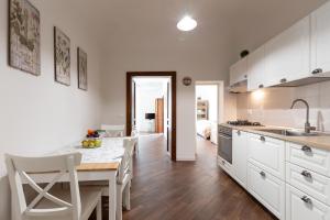 a kitchen with white cabinets and a table and chairs at Quattro Canti Charming Flat in Palermo