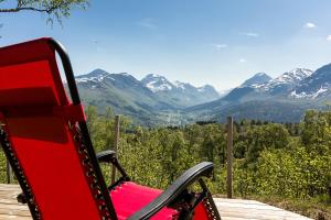 una silla roja en una terraza con montañas al fondo en Valley View, en Stranda