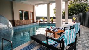 a swimming pool with two chairs and a table next to it at D'Polo Club & Spa Resort in Dharamshala