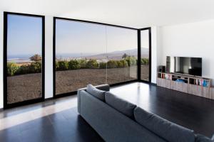 a living room with a couch and large glass windows at ICONIC VILLA LANZAROTE in Mácher