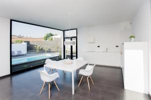 a white dining room with a white table and white chairs at ICONIC VILLA LANZAROTE in Mácher