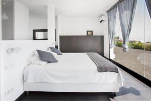 a bedroom with a white bed and a large window at ICONIC VILLA LANZAROTE in Mácher +21 photos