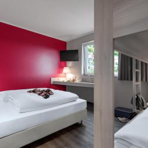 una camera d'albergo con una parete rossa e 2 letti di Serways Hotel Lüneburger Heide West a Behringen