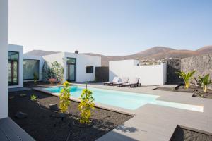 a villa with a swimming pool with mountains in the background at ICONIC VILLA LANZAROTE in Mácher