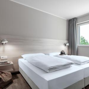 two white beds in a room with a window at Serways Hotel Lüneburger Heide West in Behringen