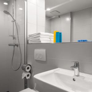 a bathroom with a shower and a sink and a mirror at Serways Hotel Lüneburger Heide West in Behringen