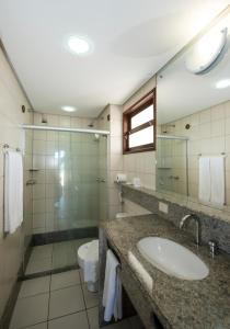 y baño con lavabo y ducha acristalada. en Blue Marlin Apartments, en Natal