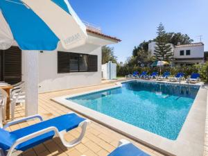 ヴィラモウラにあるSpacious Holiday Home in Vilamoura with Private Poolの家の隣にスイミングプール(椅子、パラソル付)