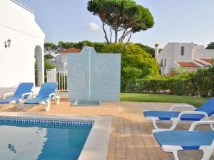 ヴィラモウラにあるSpacious Holiday Home in Vilamoura with Private Poolの家の隣のスイミングプール(青い椅子付)