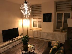 ein Wohnzimmer mit einem TV und einem Kronleuchter in der Unterkunft Zimmer 1 in Erfurt