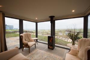 a living room with a fireplace and large windows at Elfin Cottage in Doolin